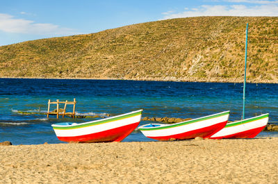 Deck chairs on beach against blue sky