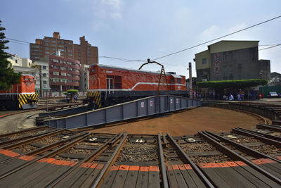 Railroad tracks by buildings in city against sky