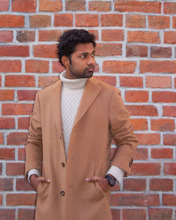 Young man standing against brick wall