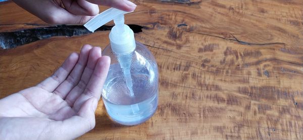High angle view of person holding bottle on table