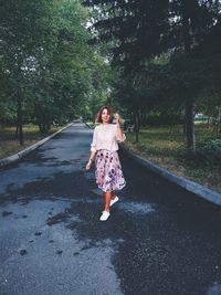 Full length of woman standing on road against trees