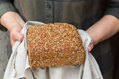 Mature senior woman holding freshly baked loaf of homemade rye bread in her hands