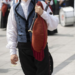 Midsection of musician playing bagpipe on street in city