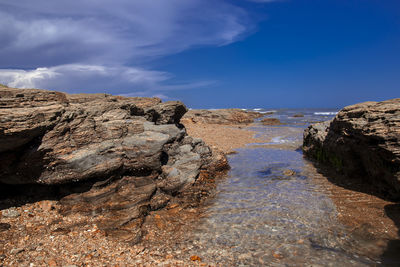 Rock formations in sea against blue sky