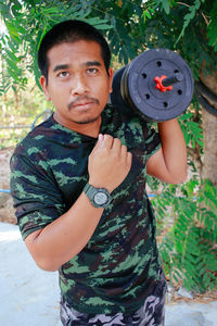 Portrait of young woman holding dumbbell in gym