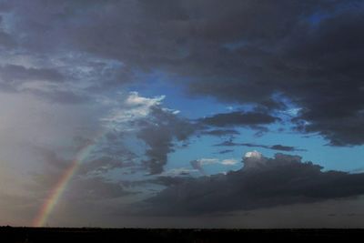 Low angle view of rainbow over landscape against sky