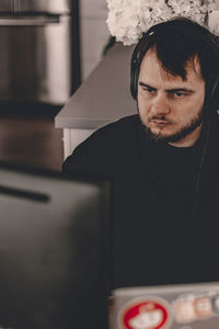 Portrait of young man using phone while sitting on table