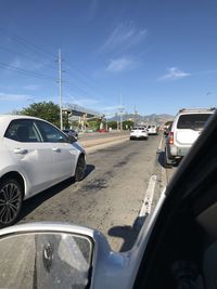 Cars on road against sky seen through car windshield