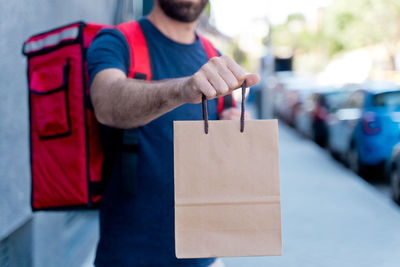 Midsection of delivery person holding cardboard bag