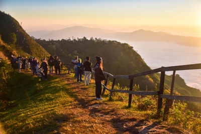 People walking on ridge against sky during sunset