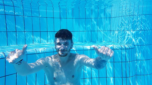 Portrait of shirtless young man gesturing thumbs up in swimming pool