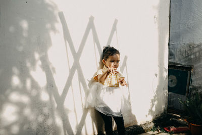 Girl dancing while standing by wall