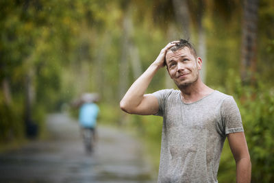 Portrait of drenched young man enjoying heavy rain in nature.