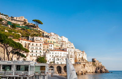 Buildings by sea against blue sky
