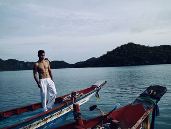 Man standing on boat in sea against sky