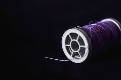 Close-up of purple thread spool over black background