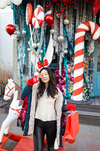 Attractive asian girl with gift bag posing on a festive city street decorated for christmas