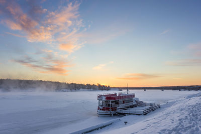 Scenic view of snow covered field against sky during sunset