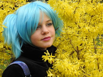 Close-up of thoughtful woman standing by yellow flowering plant