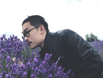Close-up of young man smelling lavenders blooming outdoors