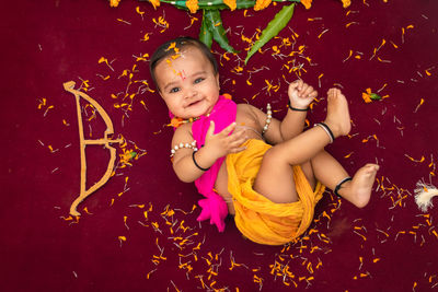 Cute indian boy dresses as lord rama with bow and flowers from top angle