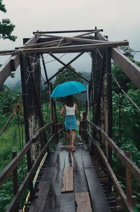 Rear view of woman standing on footbridge