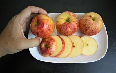 High angle view of hand holding apple on table