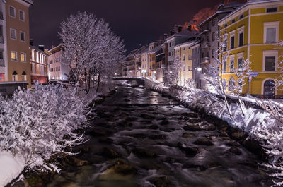 Snow covered houses and trees in city at night