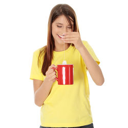Portrait of a beautiful young woman drinking water against white background