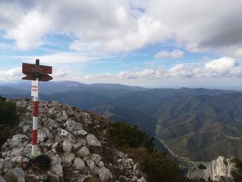 Road sign on mountain against sky