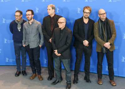 Portrait of friends standing against blue wall