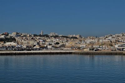 Town by sea against clear blue sky