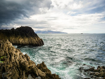 Scenic view of rocks in sea against sky