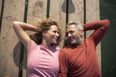 Smiling mature couple lying on jetty floorboard