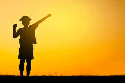 Silhouette man standing on field against sky during sunset