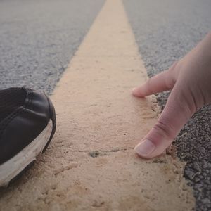 Cropped hand of woman on road