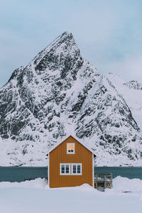 House on snow covered mountain against sky