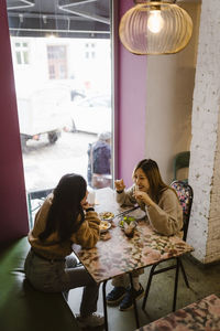 High angle view of female friends communicating while having lunch at restaurant