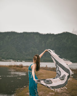 Happy woman standing on shore against clear sky