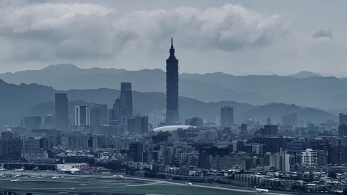 Modern buildings in city against cloudy sky