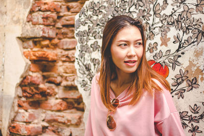 Portrait of young woman standing against wall