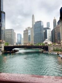 River by modern buildings against sky in city