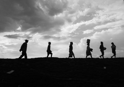 Silhouette people standing on field against sky