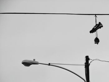 Low angle view of bird perching on cable against sky