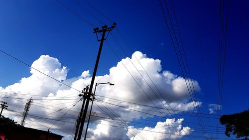 Low angle view of electricity pylon against blue sky