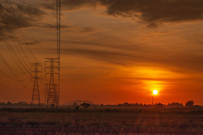 Electricity pylon on field against sky during sunset