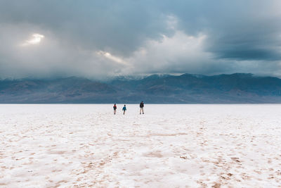 People on beach against sky during winter