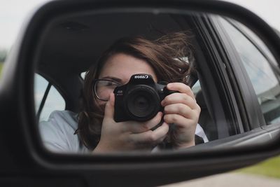 Portrait of woman photographing car
