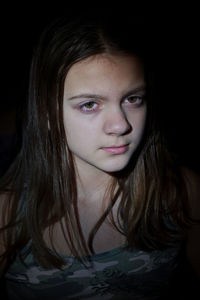 Close-up portrait of a beautiful young woman over black background