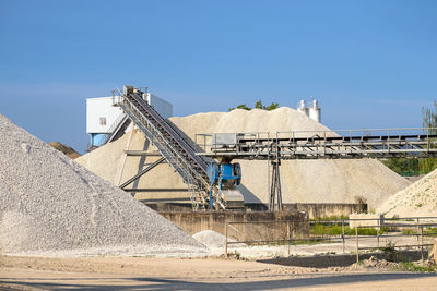 A system of interconnected conveyor belts over heaps of gravel an industrial cement plant.